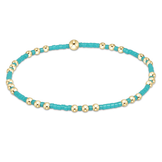 Turquoise and gold beaded bracelet on a white background